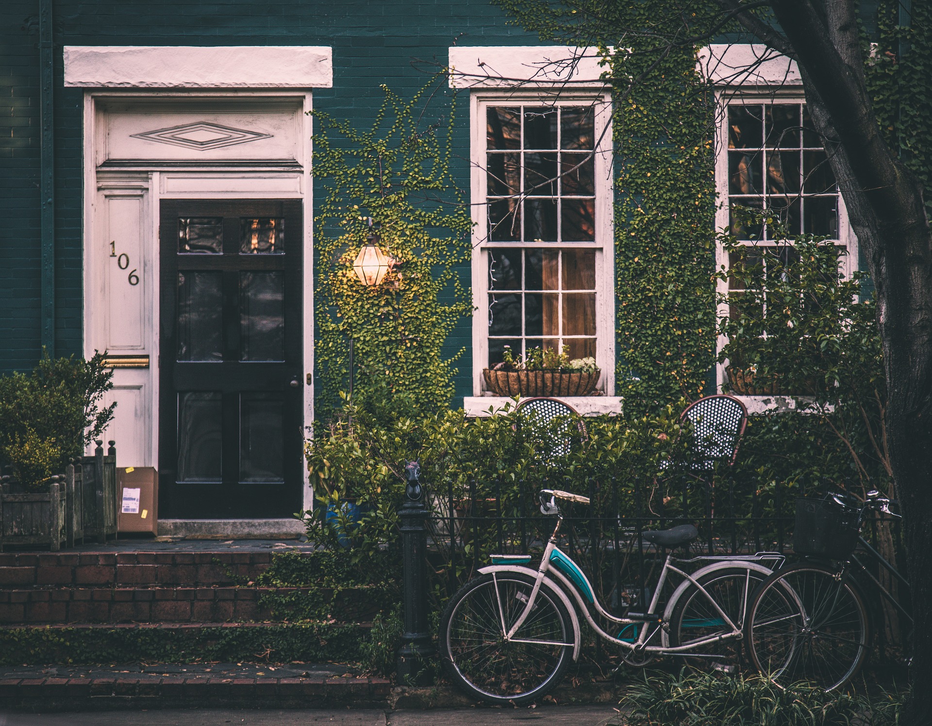 Vintage bicycle leaning against fence near front door of a house