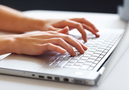 Hands typing on a laptop