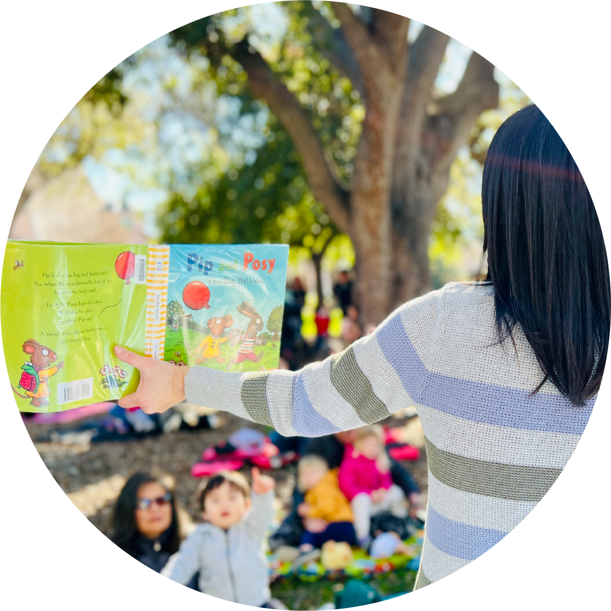 children being read a book in park