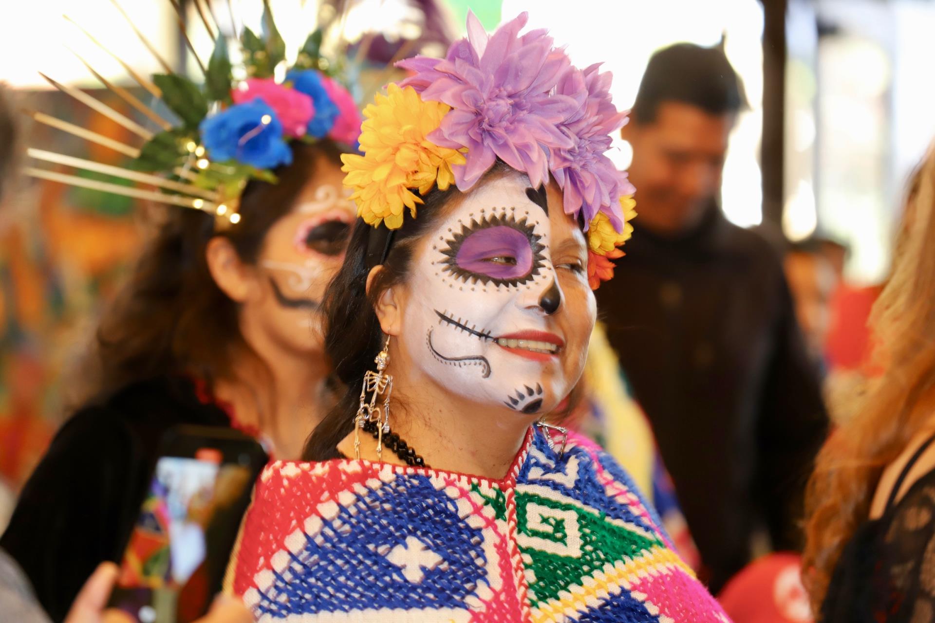 Woman wearing a colorful marygold crown and día de muertos make up